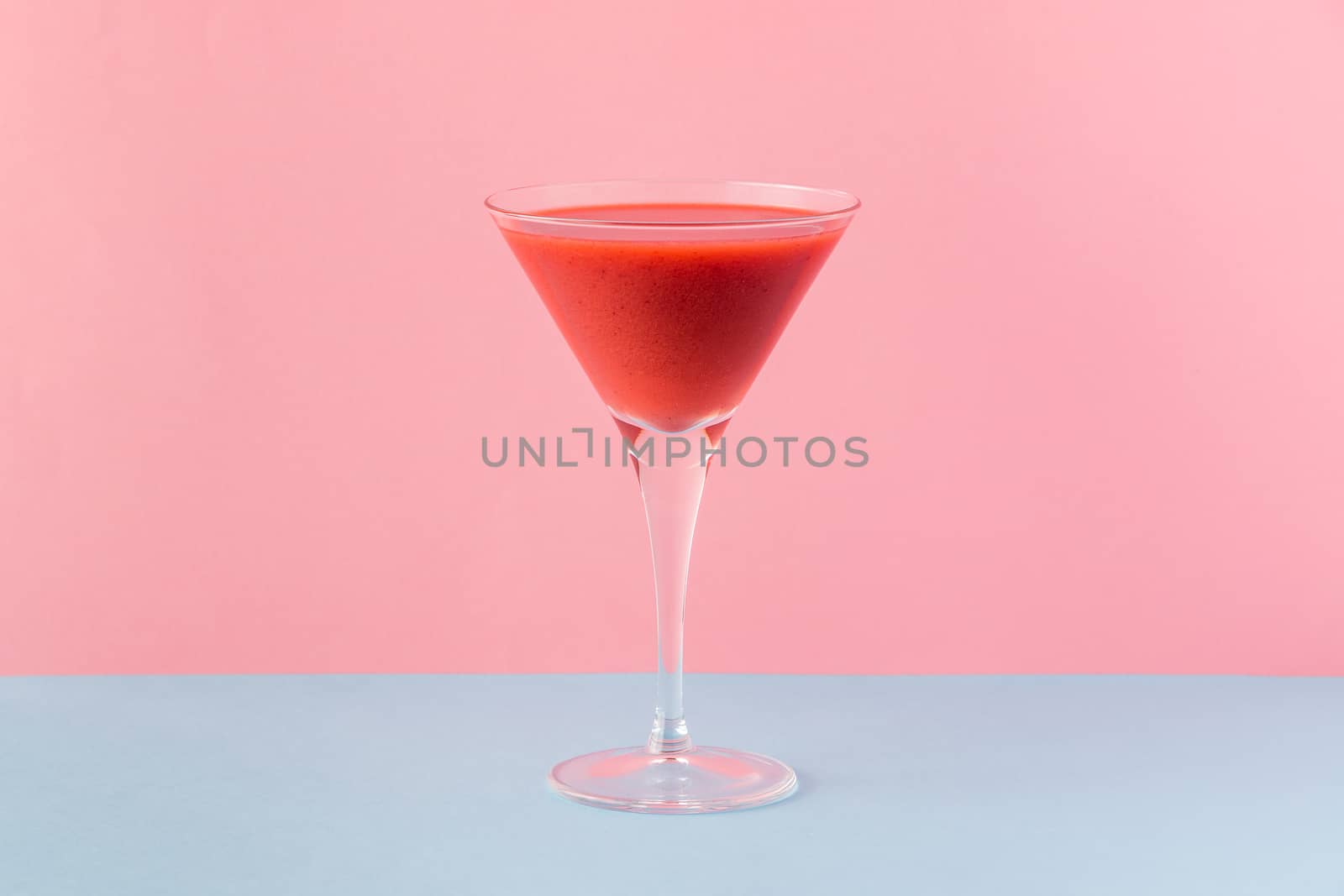 Strawberry smoothie cup on a pink and light blue background. Minimalist image.