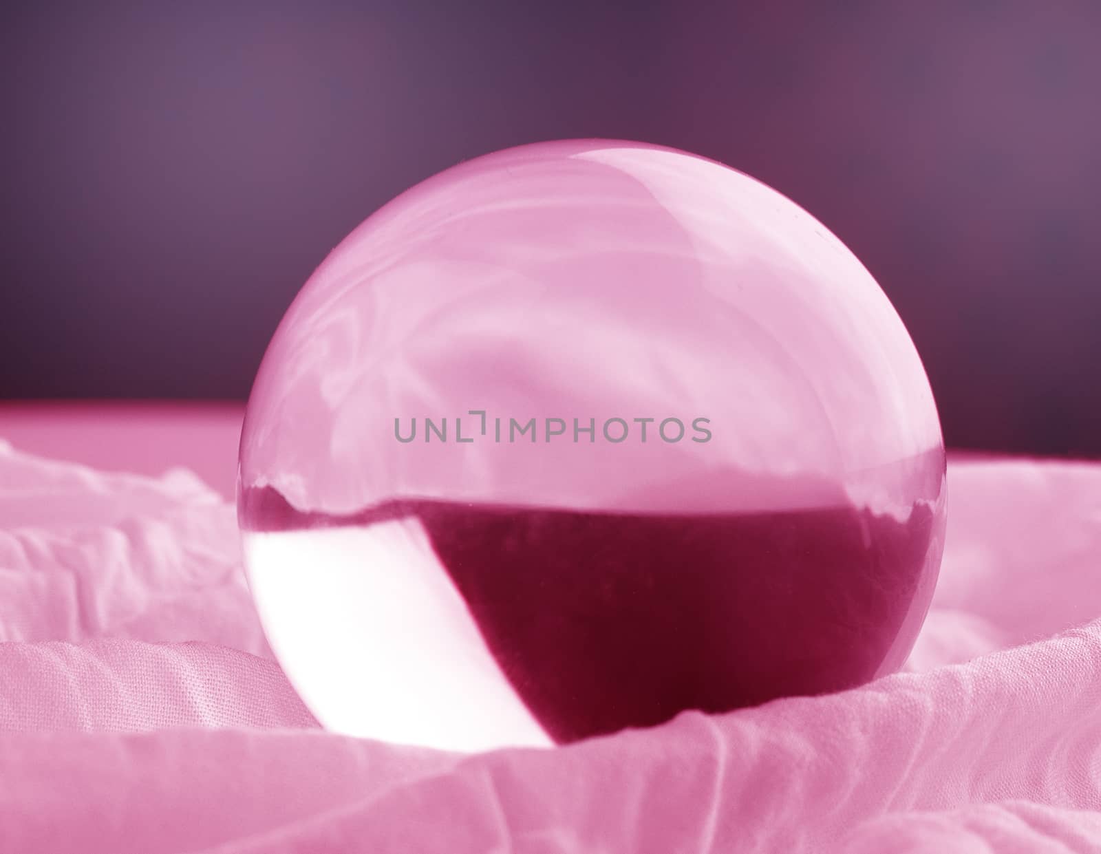 Crystal glass ball sphere transparent on pink gradient background.