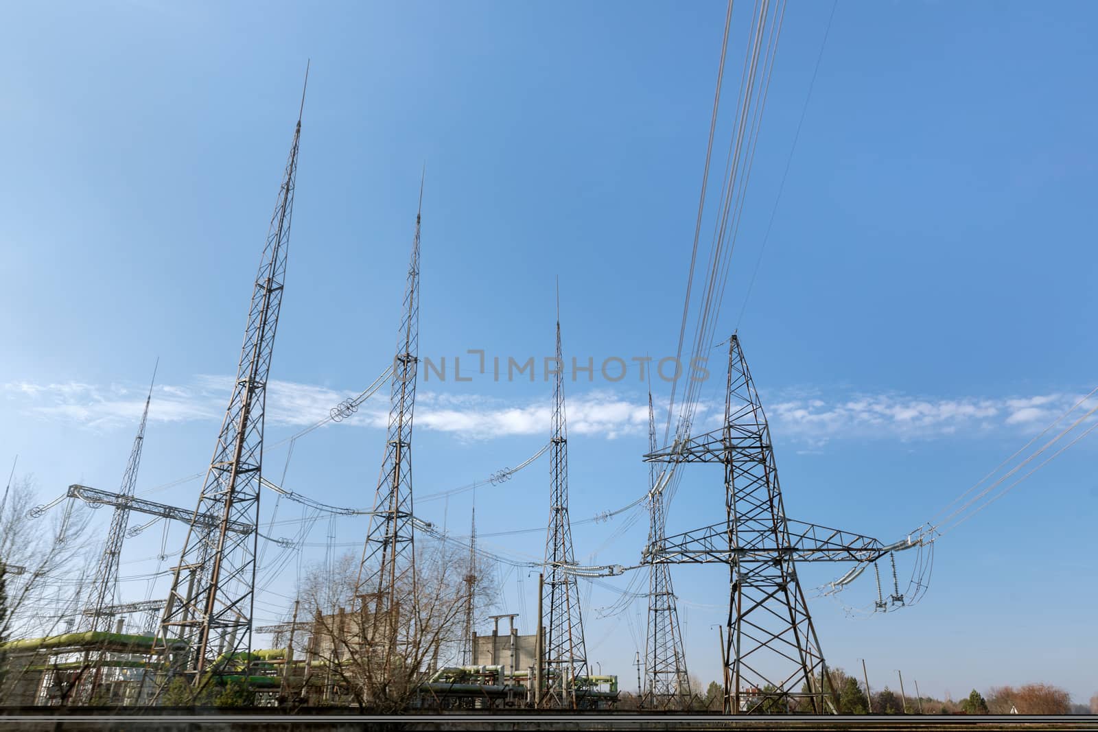 Large pylons at power distributing station under blue sky