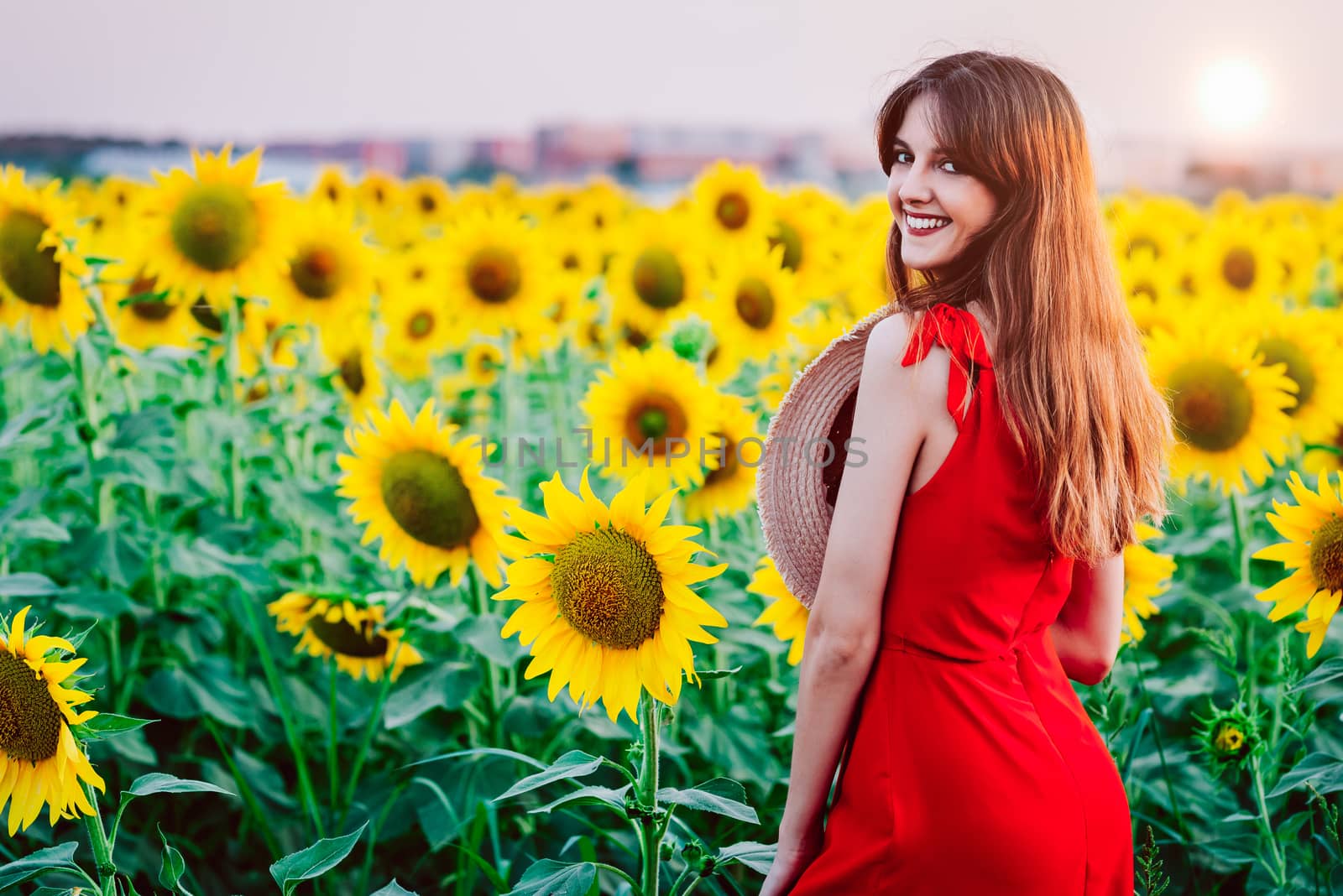 woman with red dress and hat in sunflowers field.