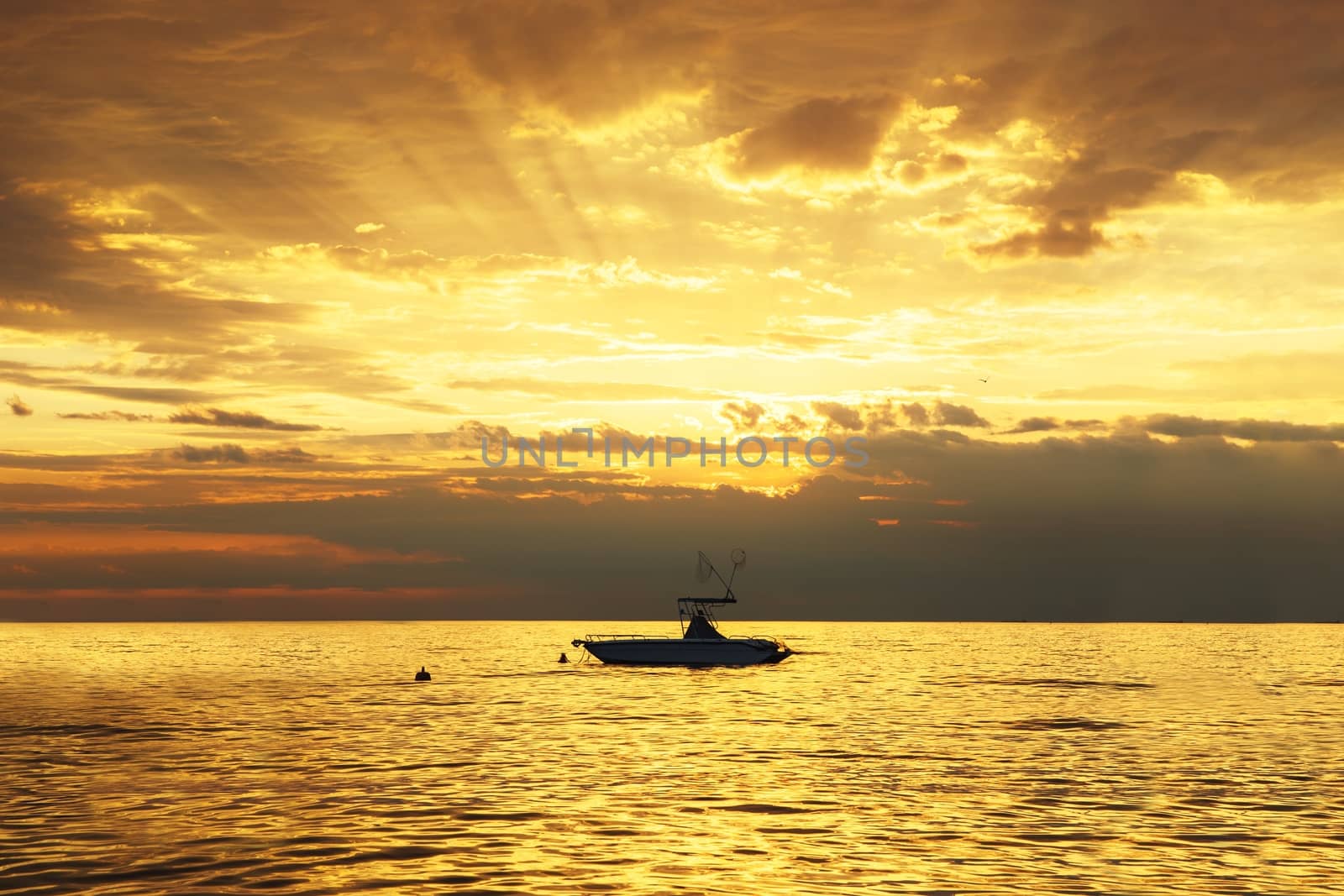 Golden sunset with the silhouette of small boat