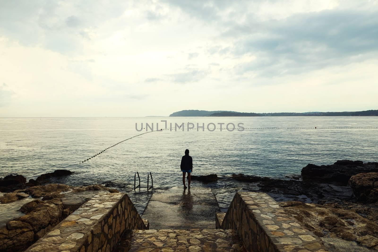 Woman standing on concrete pier in gloomy weather closeup photo