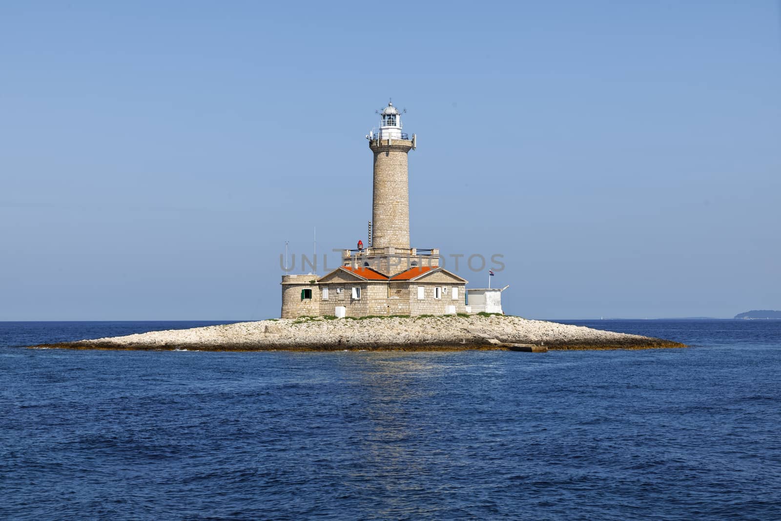 old stone lighthouse on small island closeup photo