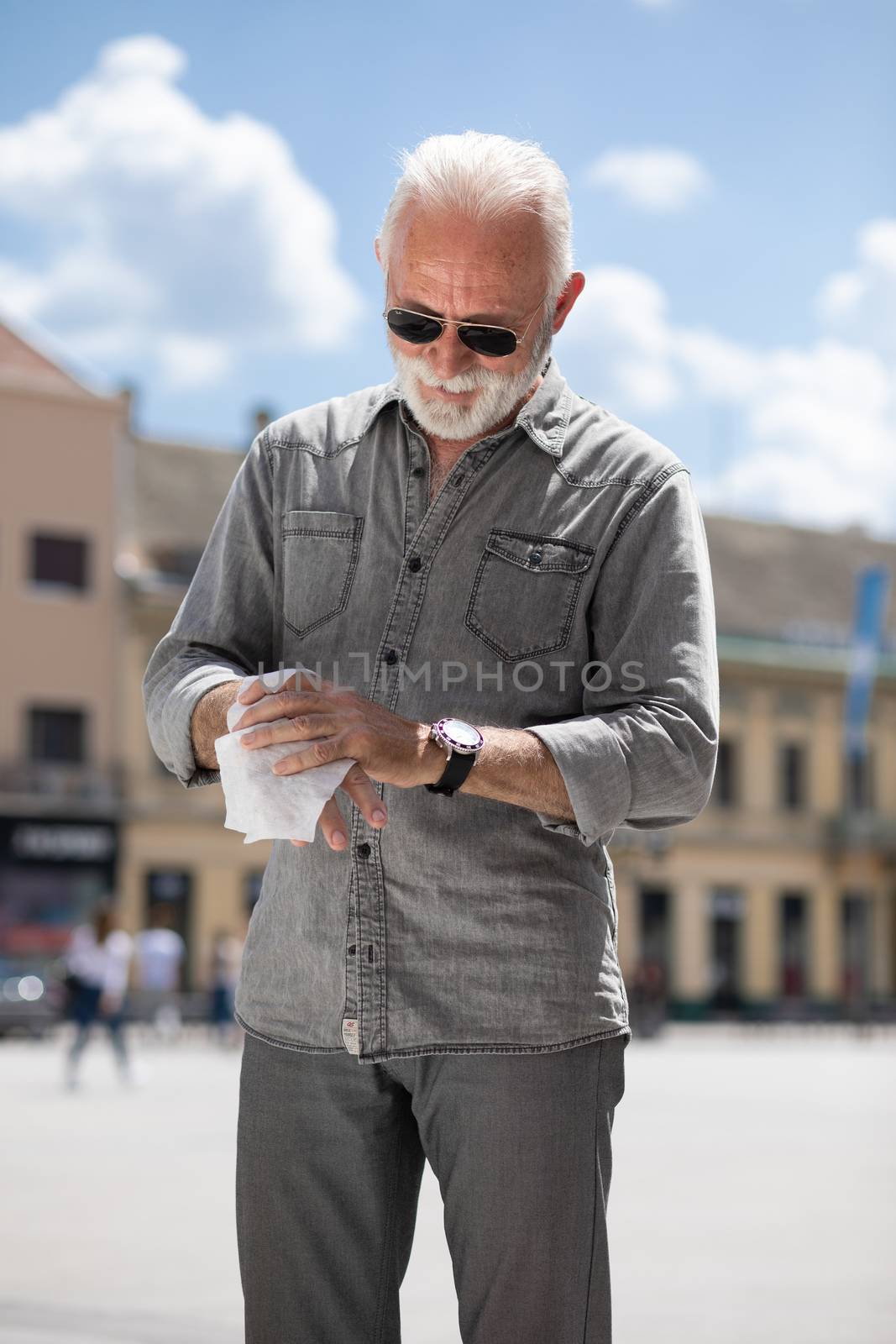 Old man cleaning hands with wet wipes outdoor by adamr