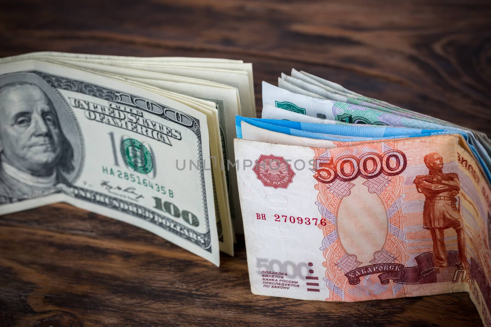 russian rubl and us dollar banknotes standing on brown wood surface close-up with selective focus and blur