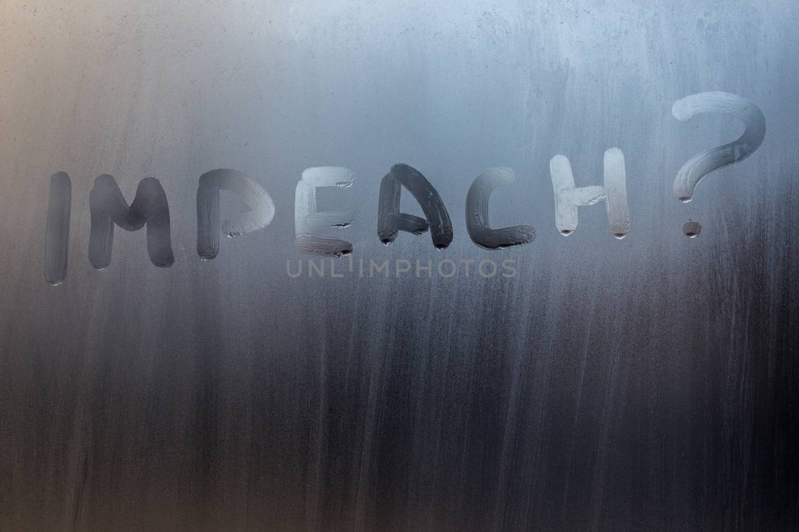 the question impeach written on wet window glass close-up with blurred background.