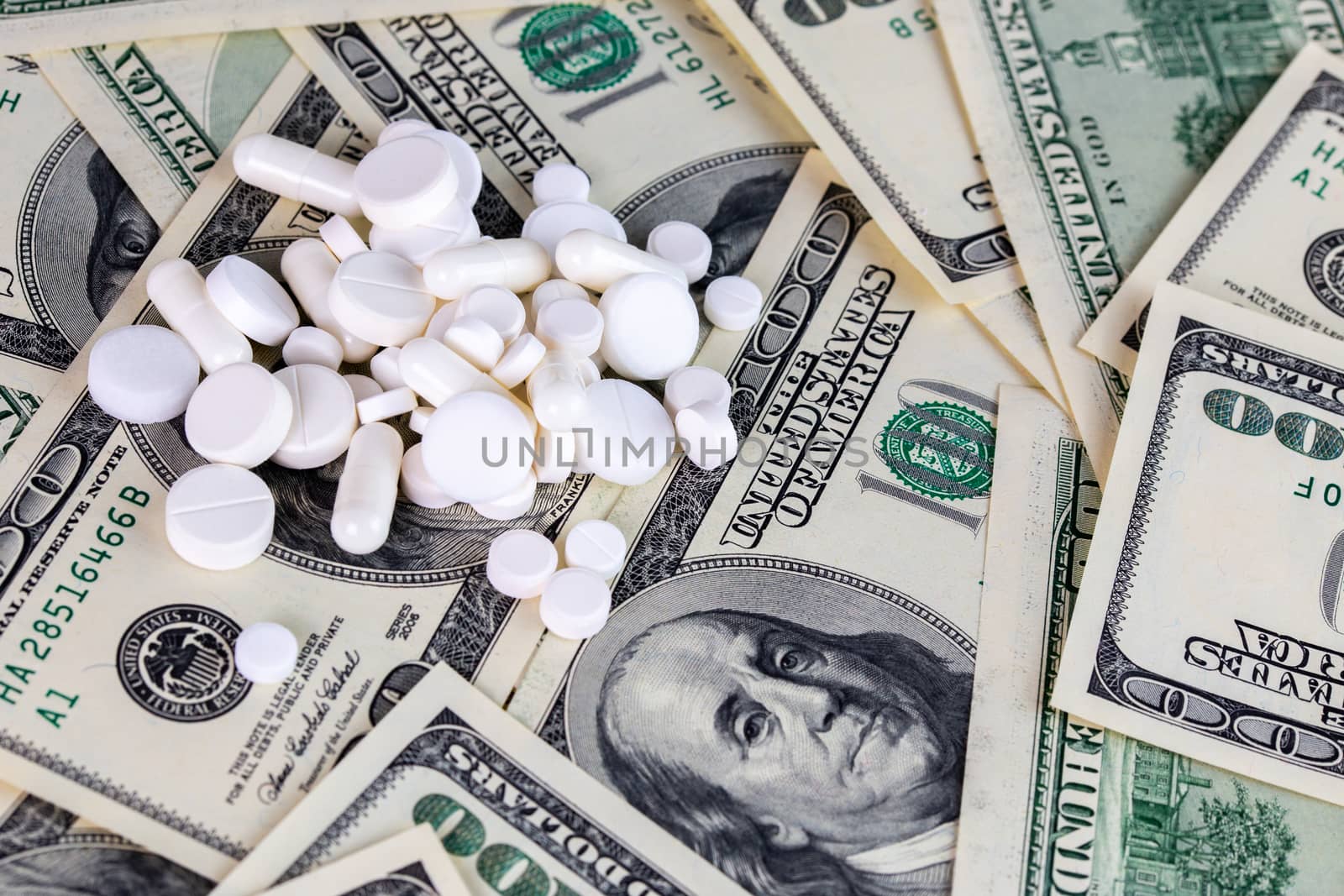 handful of white pills on dollar bills close-up with selective focus