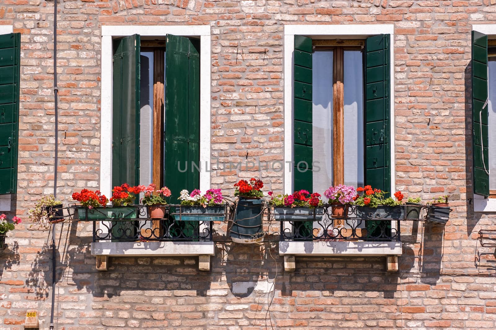 Traditional Italian balconies with perlagonium filled window boxes. Venice, Italy.