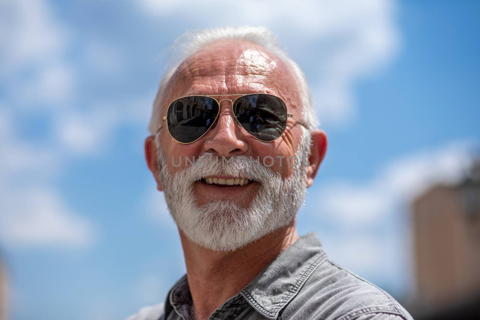 Happy rich old man with beard and sun glasses on street smiling, portrait