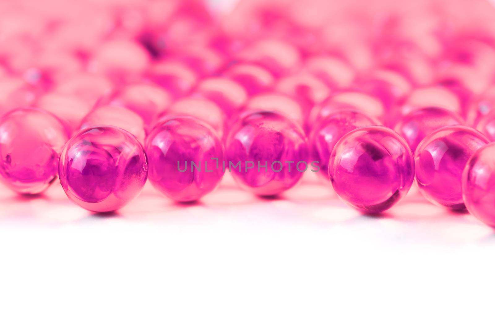plastic pink spherical ball capsules with selective focus isolated on white background.