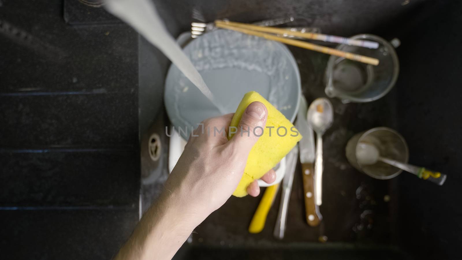 Washing dirty dishware in black sink closeup photo