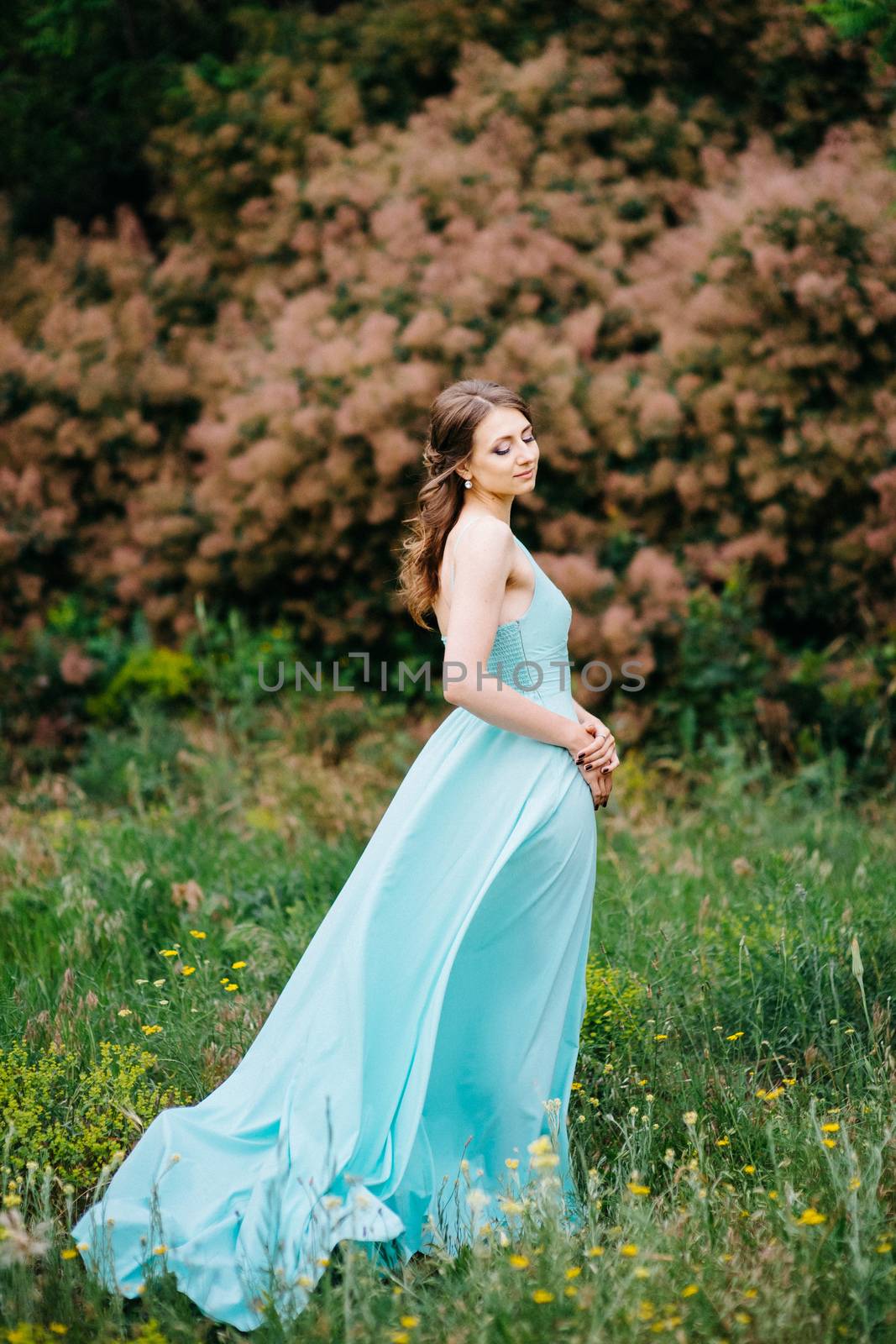 Happy girl in a turquoise long dress in a green park by Andreua