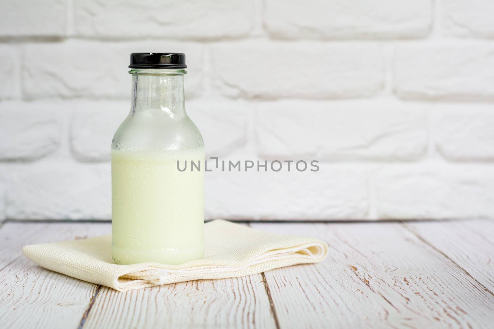 Bottle of fresh milk on white table cloth with wall in kitchen with copy space for your text. High calcium and vitamins. Good beverage for morning.