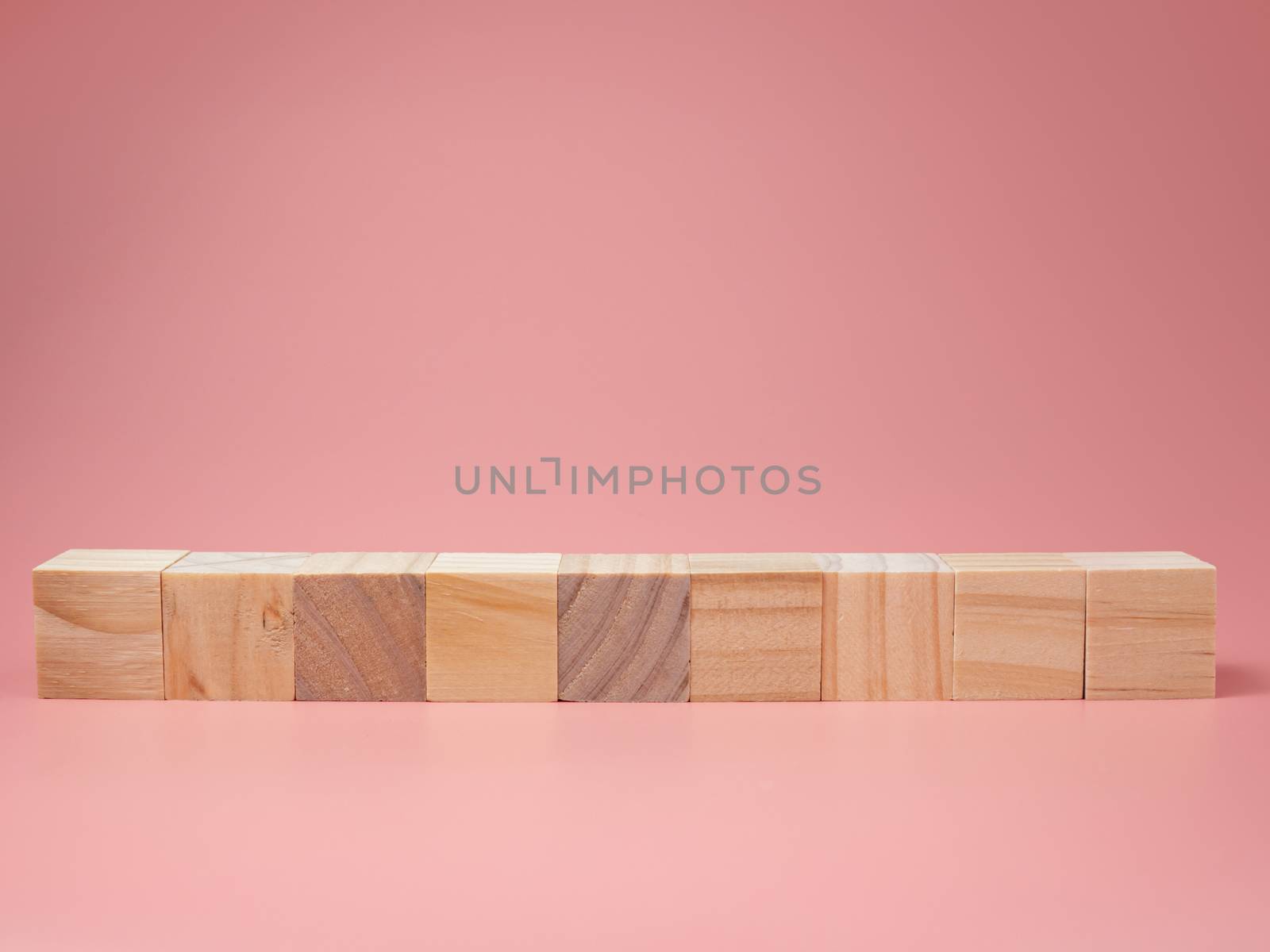 An empty wooden cube lined up on a pink background. For new ideas to be put into the picture.