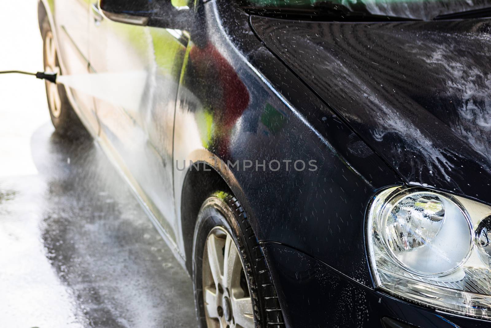 Washing and cleaning car in self service car wash station. Car washing using high pressure water in Bucharest, Romania, 2020