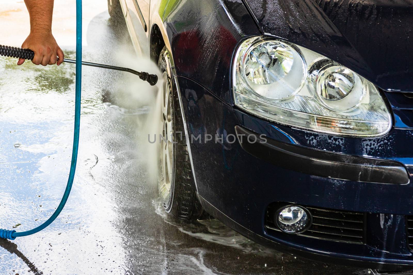 Washing and cleaning car in self service car wash station. Car washing using high pressure water in Bucharest, Romania, 2020