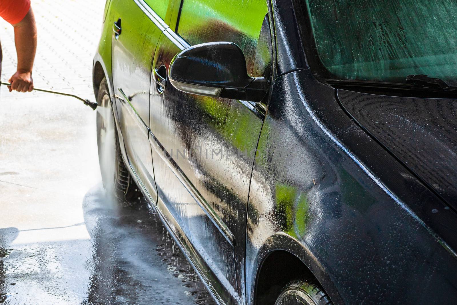 Washing and cleaning car in self service car wash station. Car washing using high pressure water in Bucharest, Romania, 2020