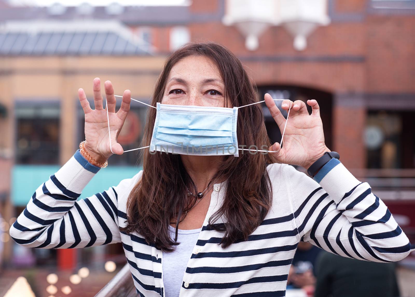 Asian woman wearing a face mask and showing how to put on the mask correctly