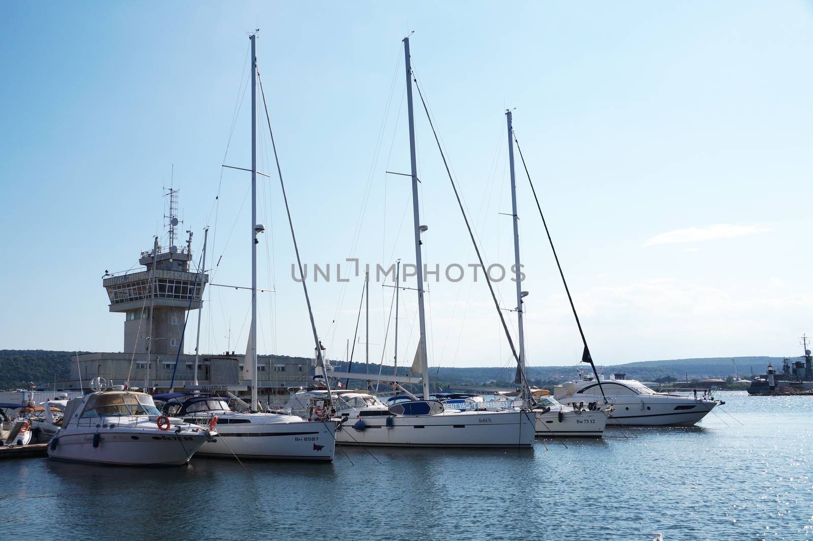 white yachts moored in the port against the backdrop of the sunset sky by Annado