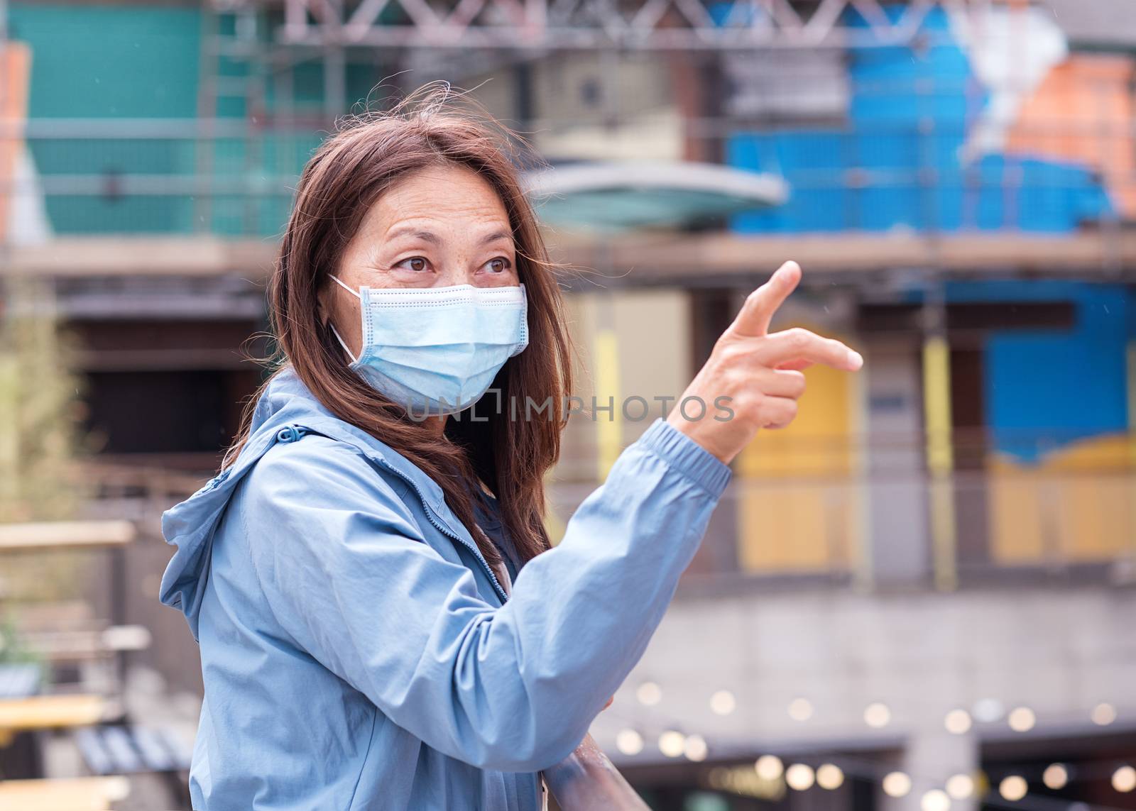 Asian woman wearing a face mask and showing something