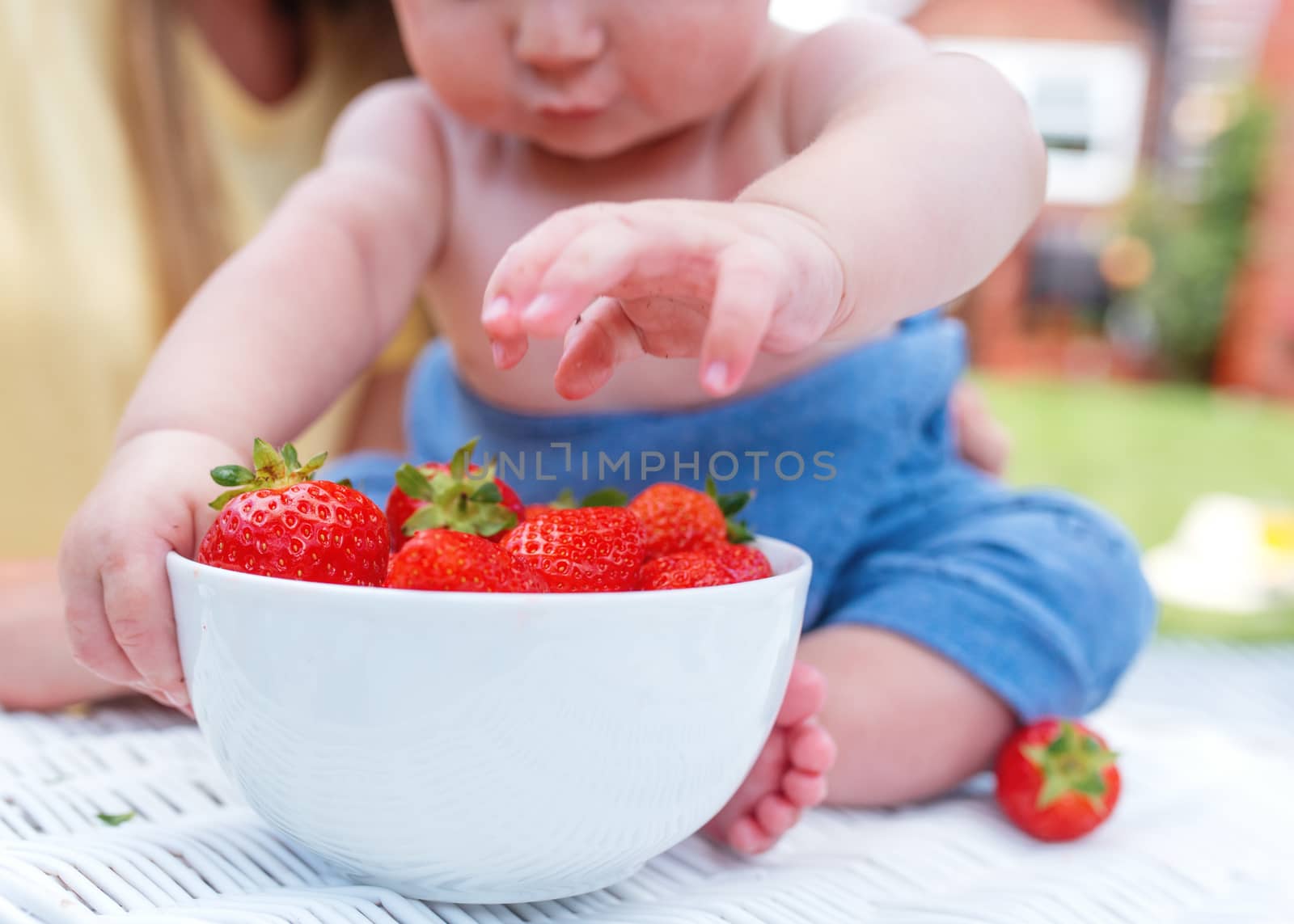 child grubbing strawberries in the bawl