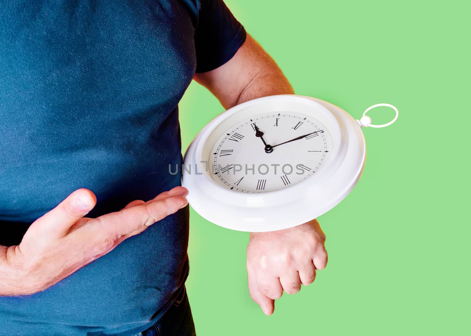 man holding clock and pointing to them on green background