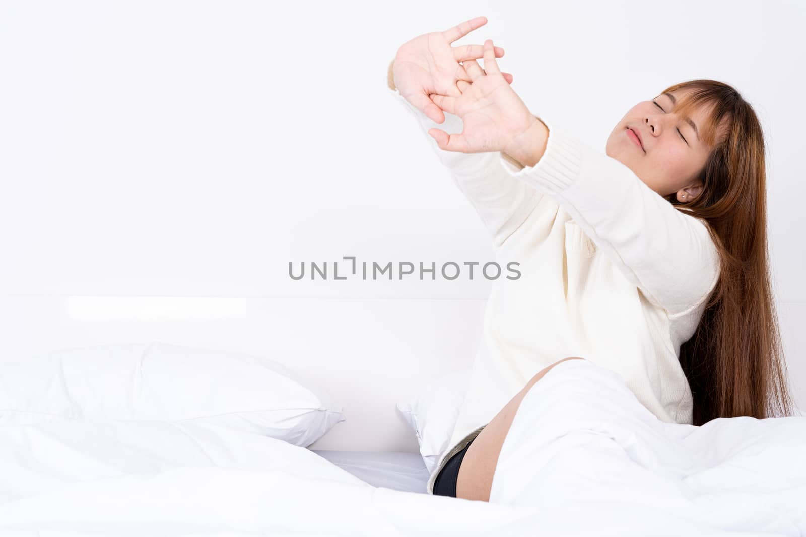 Young Asian woman stretching in bed after wake up from the good comfortable bed. Healthcare medical or daily life concept. by mikesaran