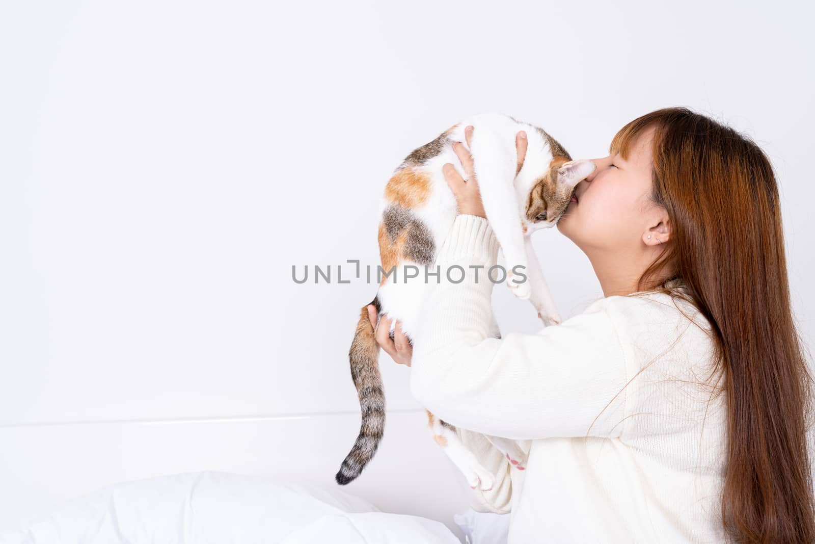 Woman at home holding and kissing her lovely fluffy cat. Multicolor tabby cute kitten. Pets and lifestyle concept. by mikesaran