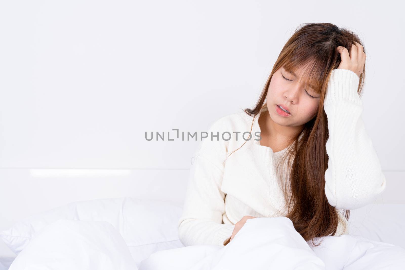 Young woman suffering from headaches after wake up on the bed. Healthcare medical or daily life concept.