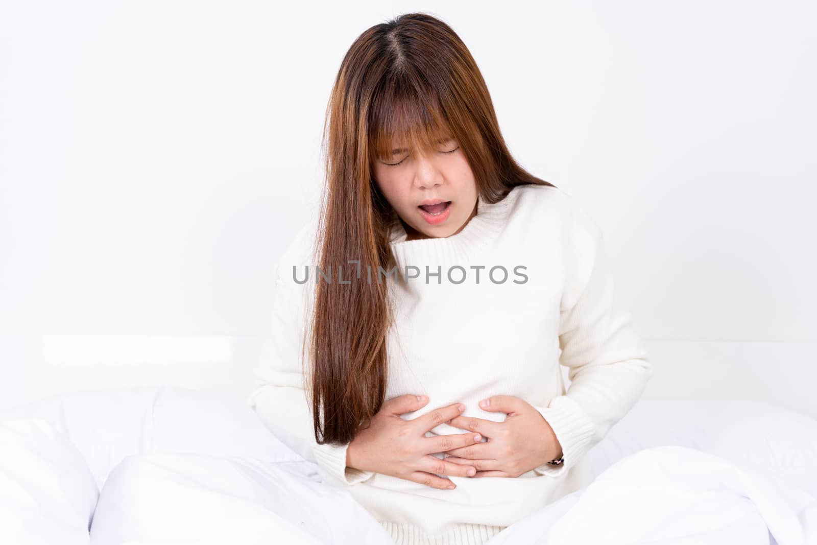 Young woman suffering stomach aches lying on the bed. Healthcare medical or daily life concept. by mikesaran