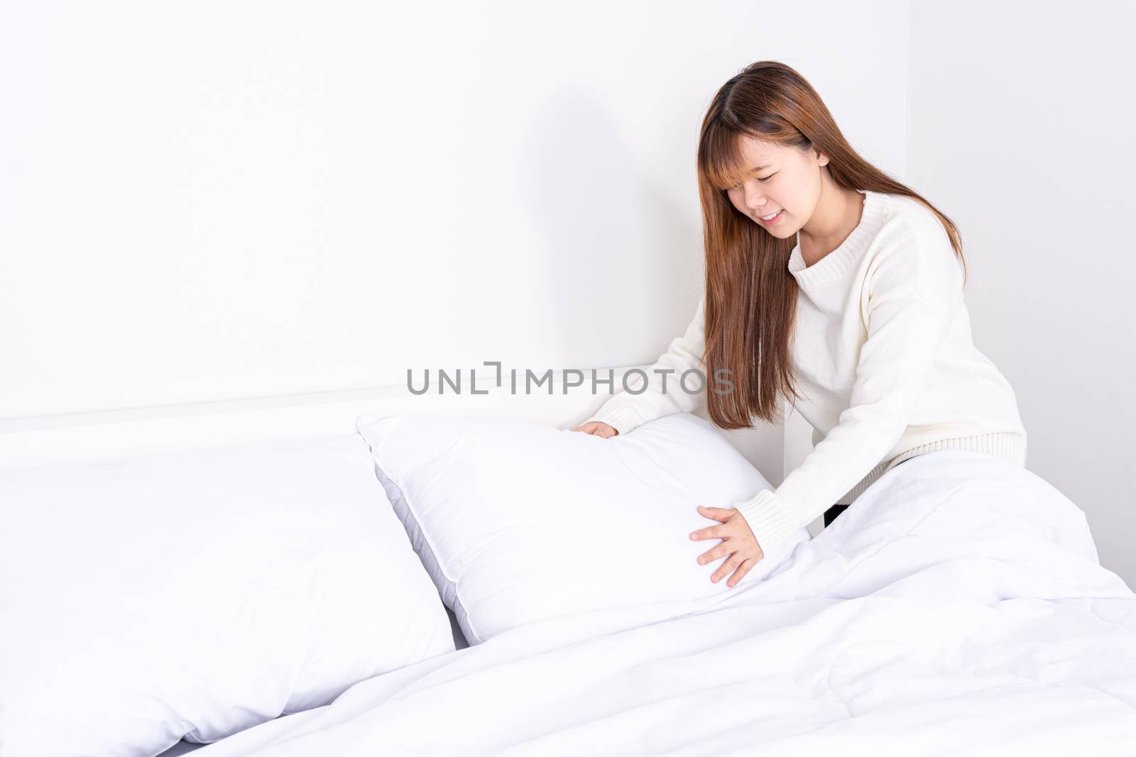 Beautiful Asian women making bed in room early in the morning. daily life concept.