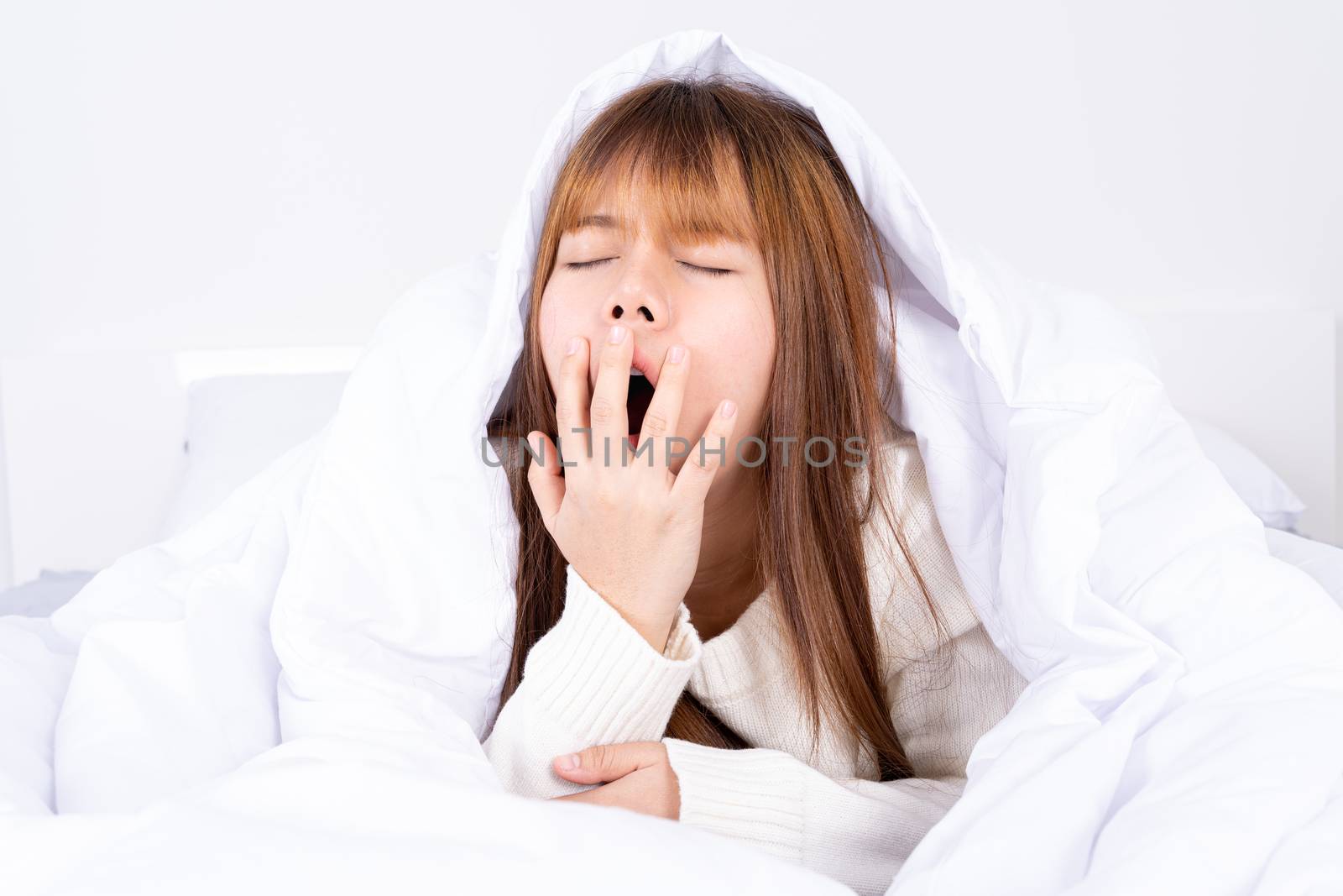 Asian woman are yawning covering open mouth with hand after she wake up. Healthcare medical or daily life concept.