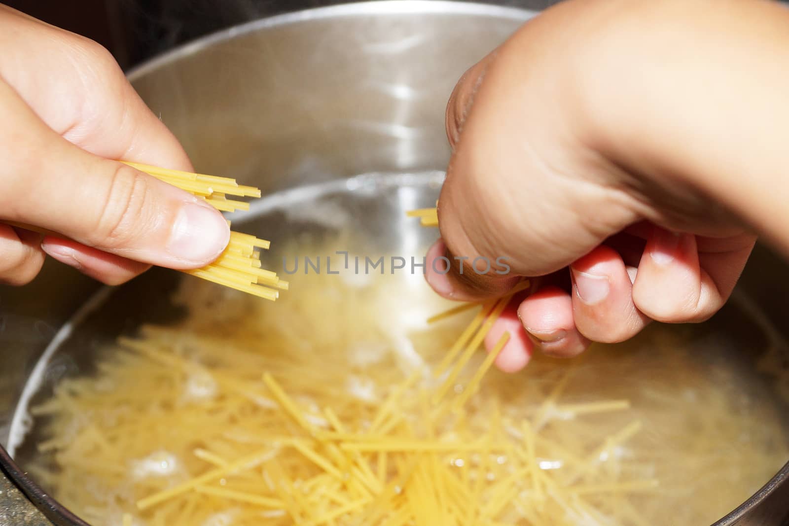 cooking spaghetti in a saucepan close up by Annado