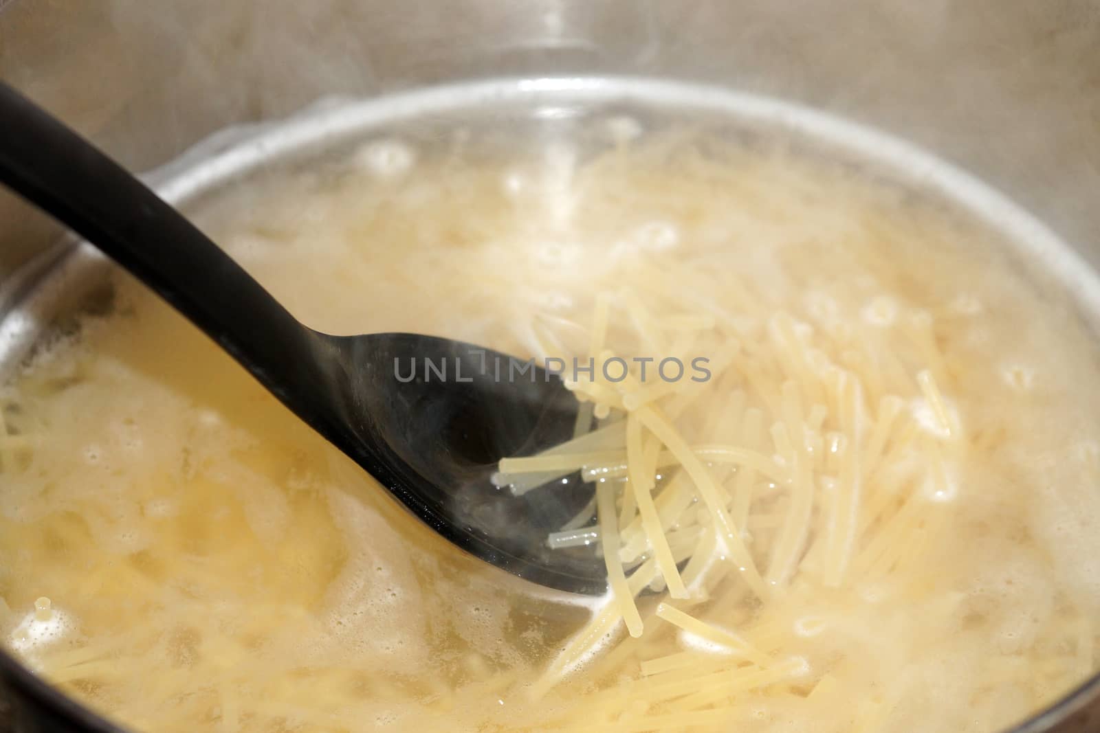 cooking spaghetti in a saucepan close up by Annado