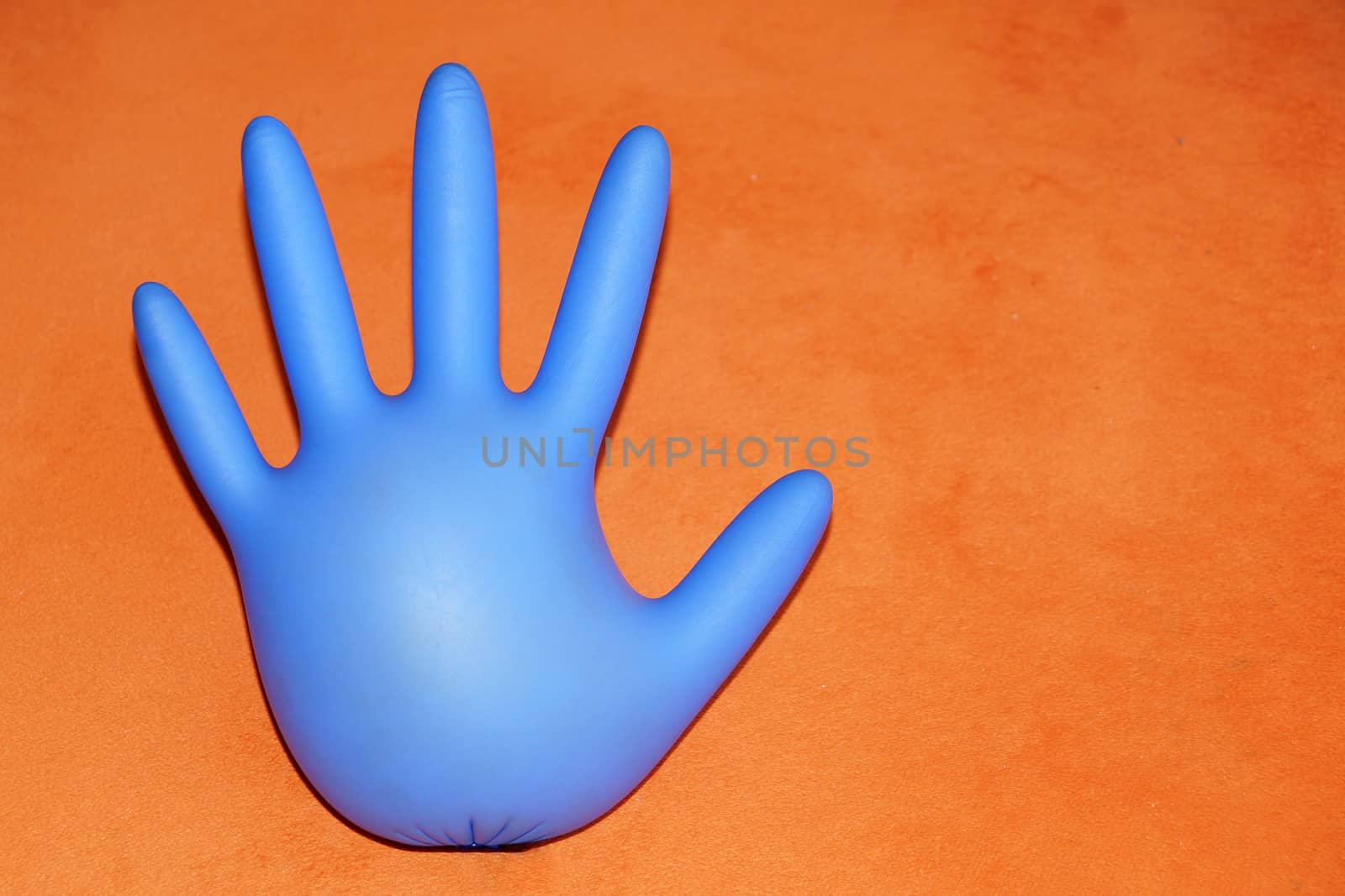 inflated rubber medical glove on orange background, copy space.