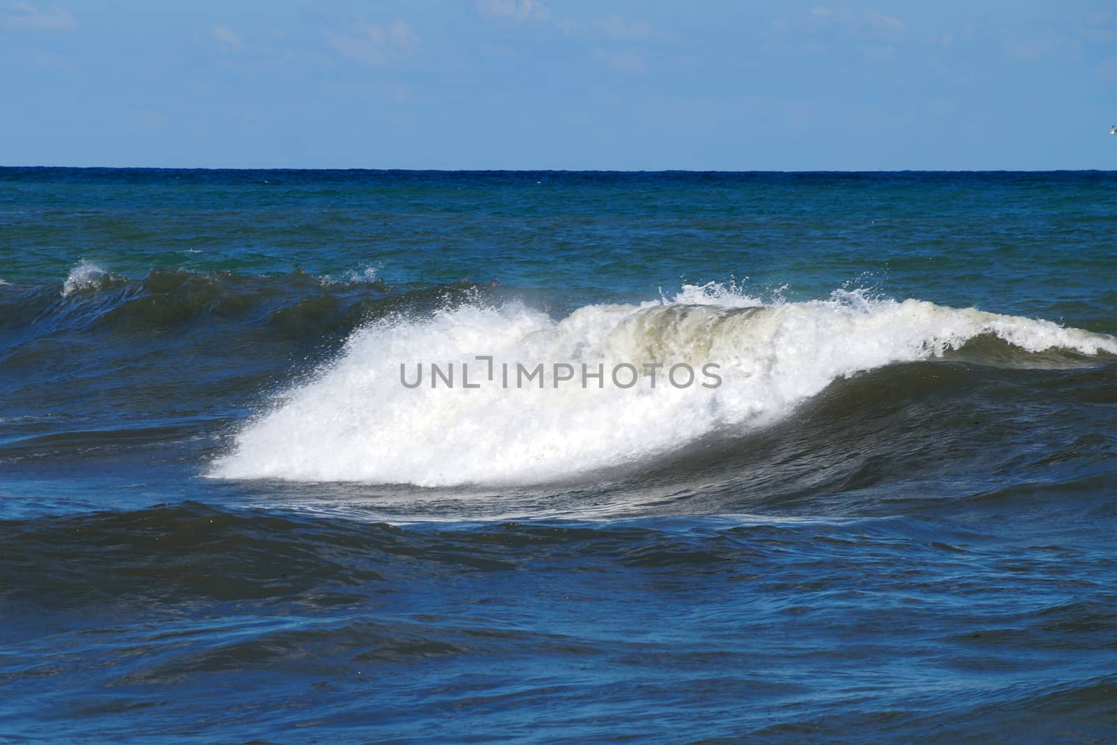 big foamy wave at sea on a sunny day.