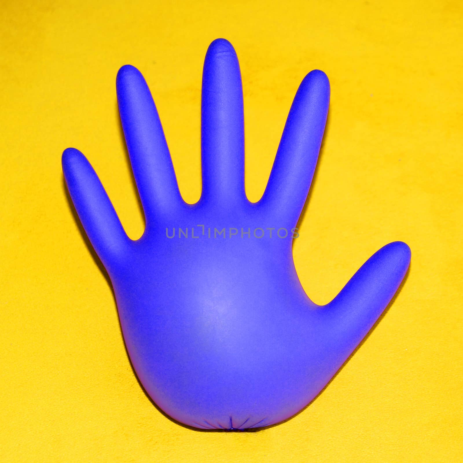 inflated rubber medical glove on yellow background, square photo by Annado
