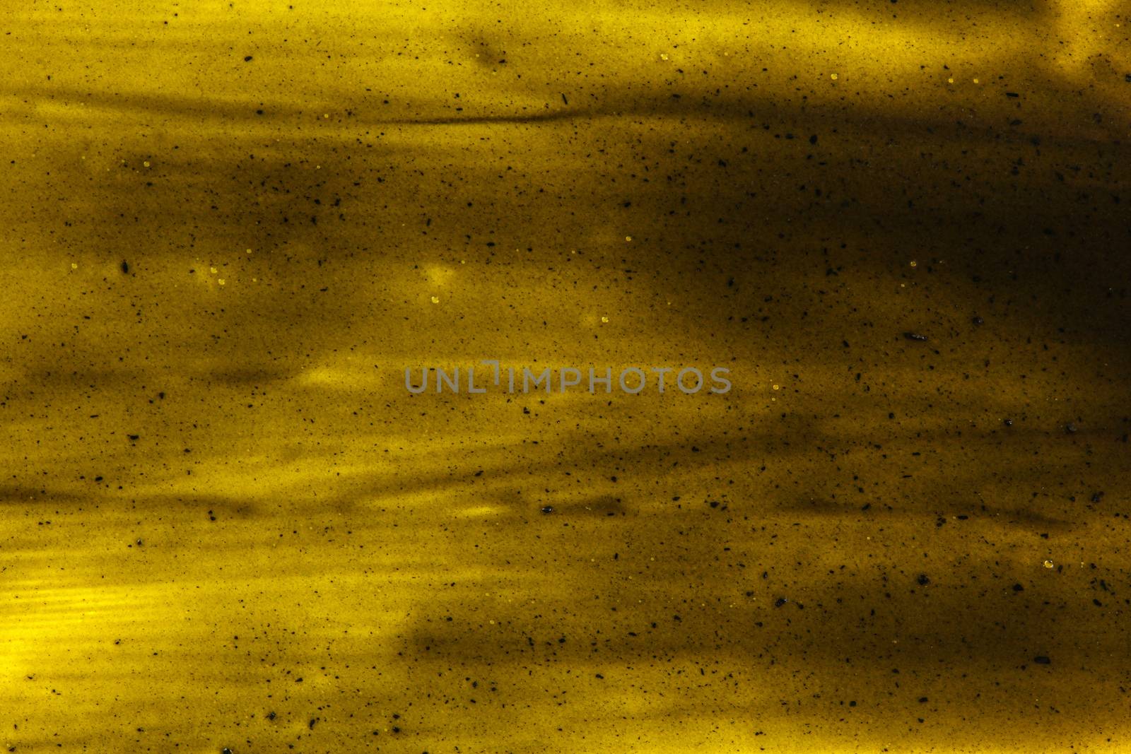 Black smears charcoal toothpaste over yellow board, abstract background by Ivanko