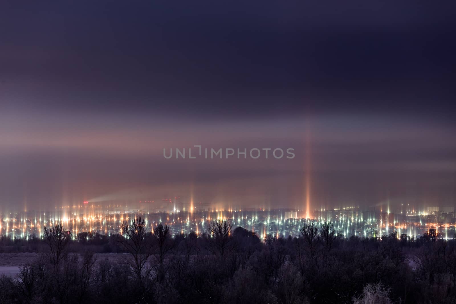 night winter cityscape with light pillars atmospheric phenomenon.