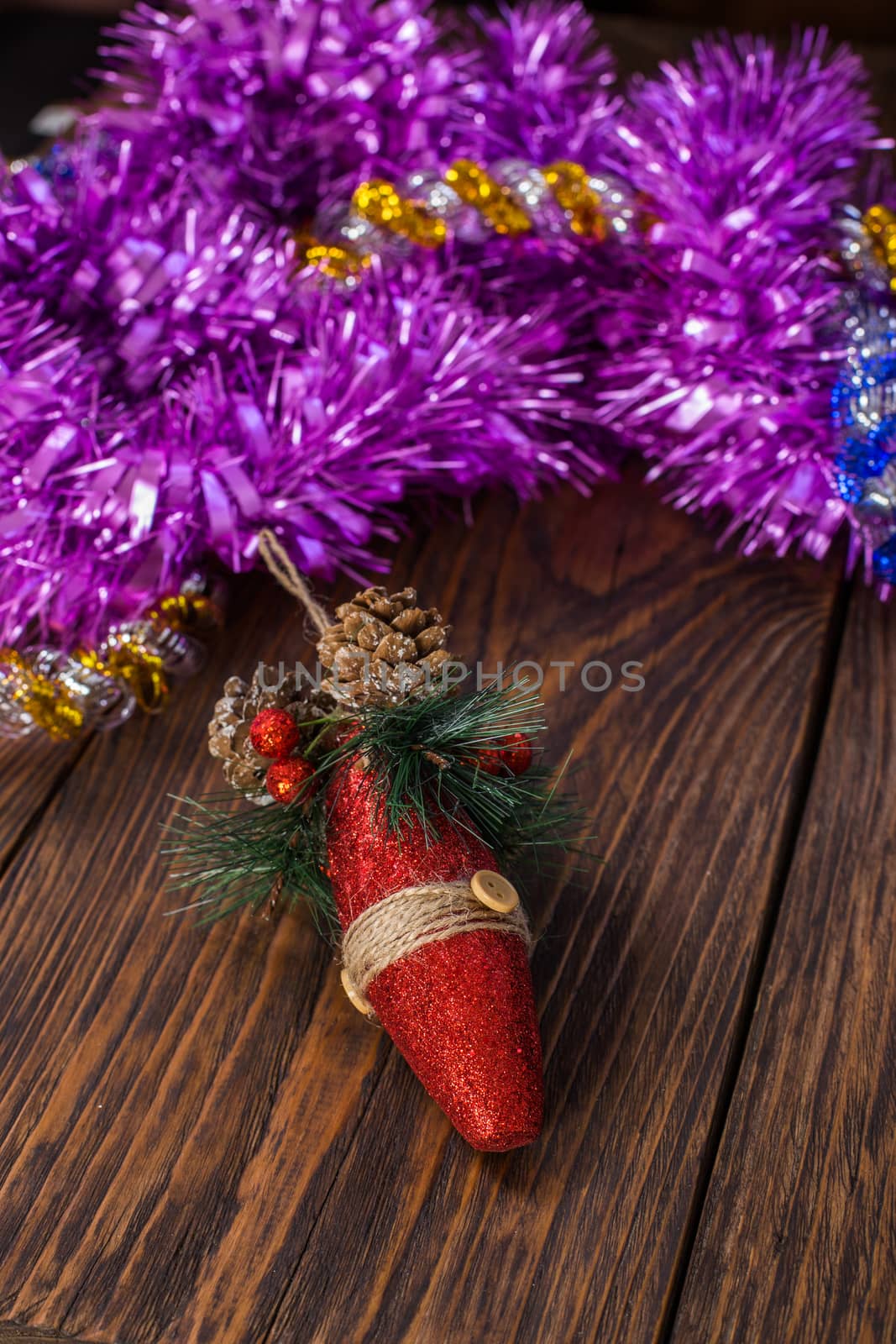 a christmas tree toy and purple tinsel on brown wood background - vertical orientation