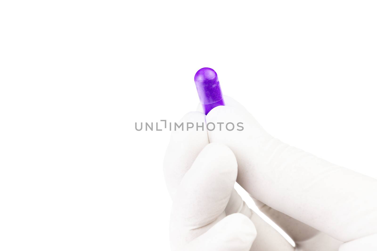 hand in medical glove holding proton purple color organic med capsule isolated on white background closeup.