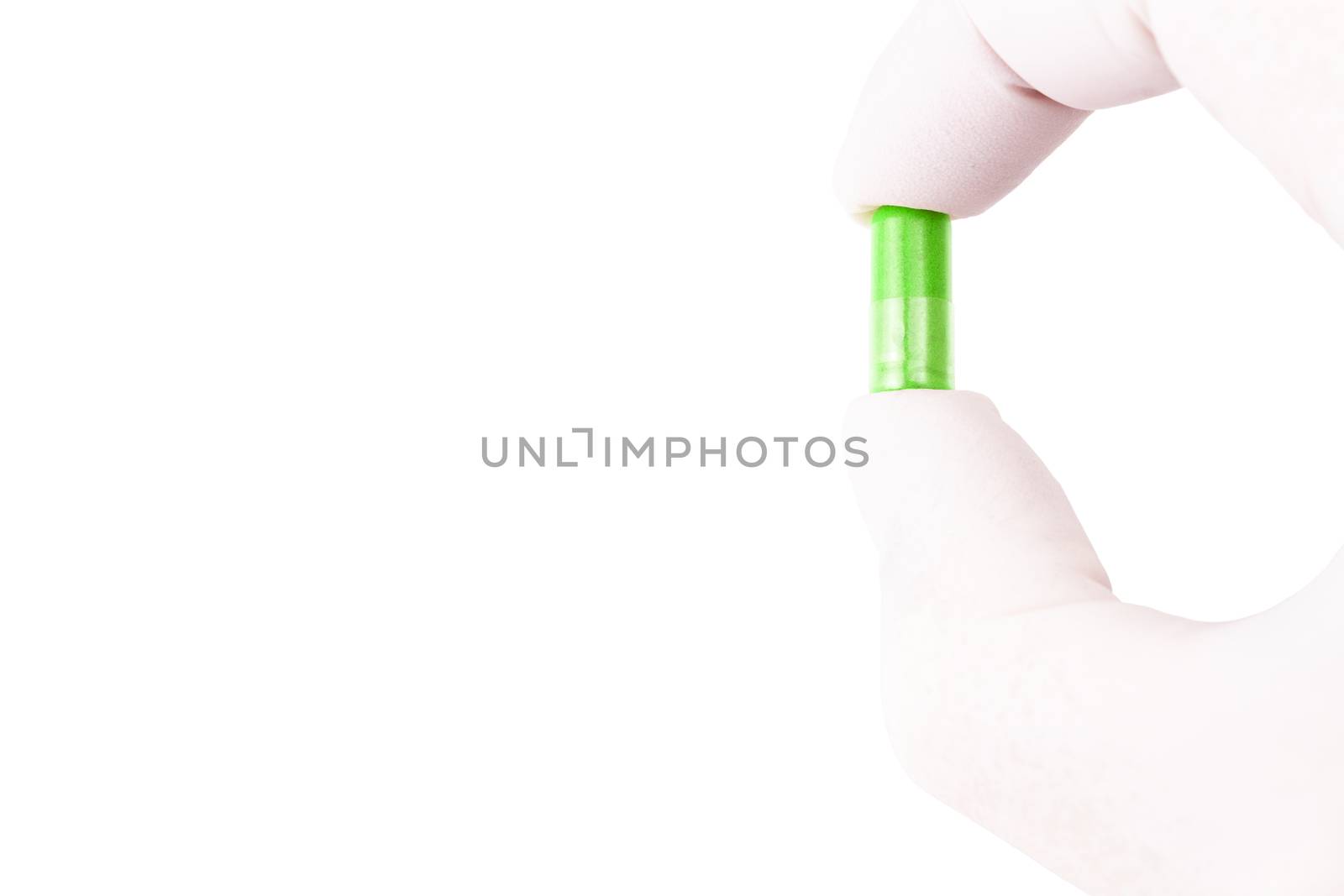 hand in medical glove holding ufo green color organic med capsule isolated on white background closeup.
