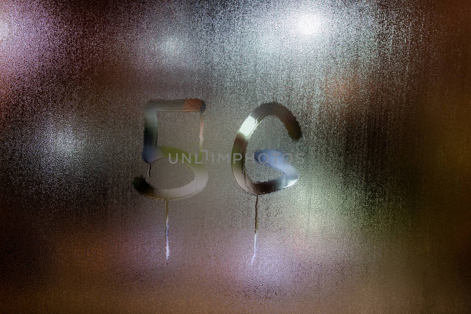 a handwritten word 5G on wet glass with blurred night lights in background.
