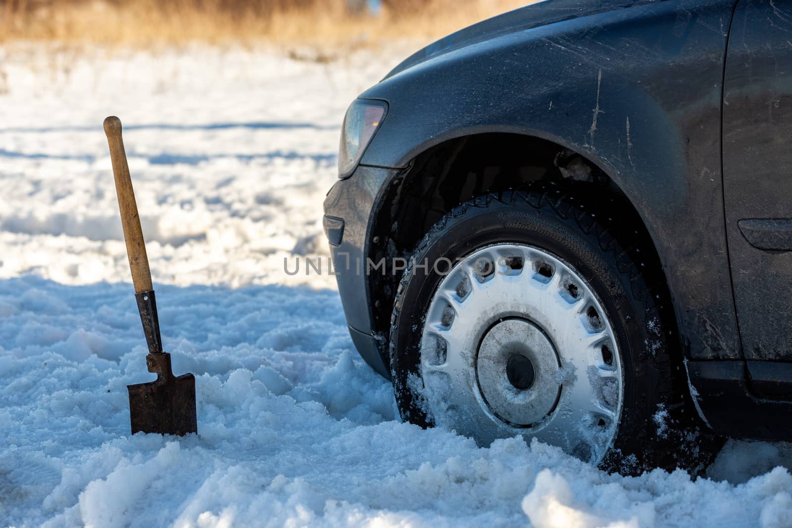 car stuck in snow offroad at daylight with shovel and selective focus.