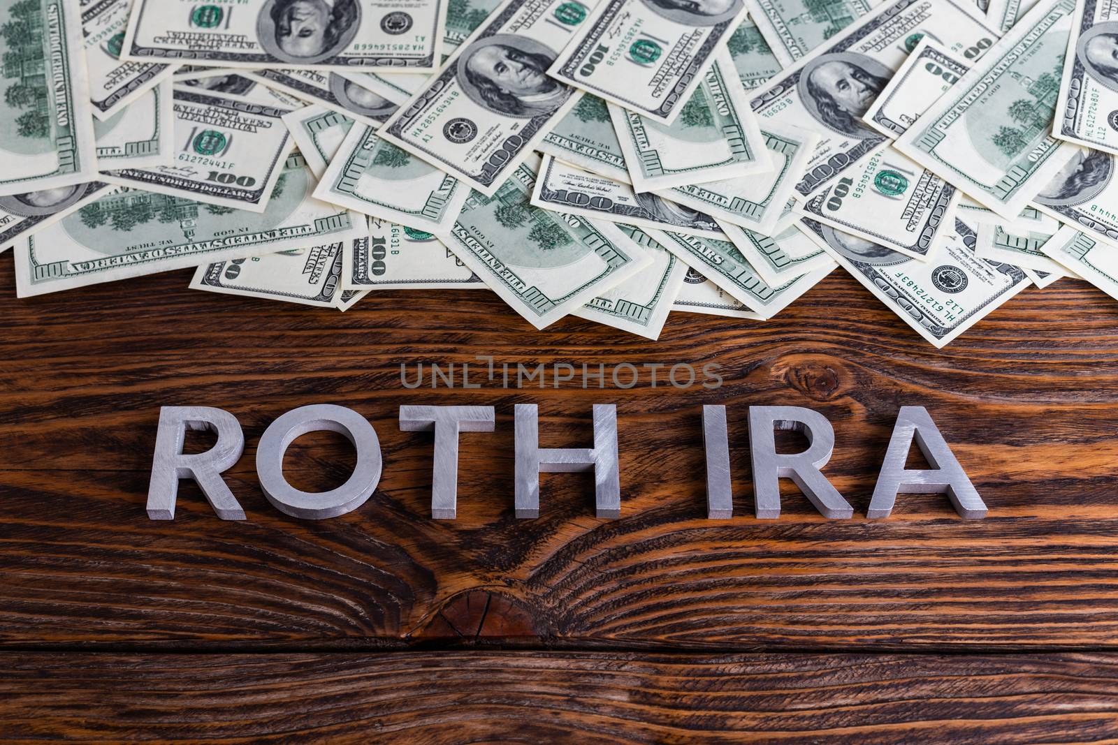 words ROTH IRA laid on wooden surface with metal letters us paper currency