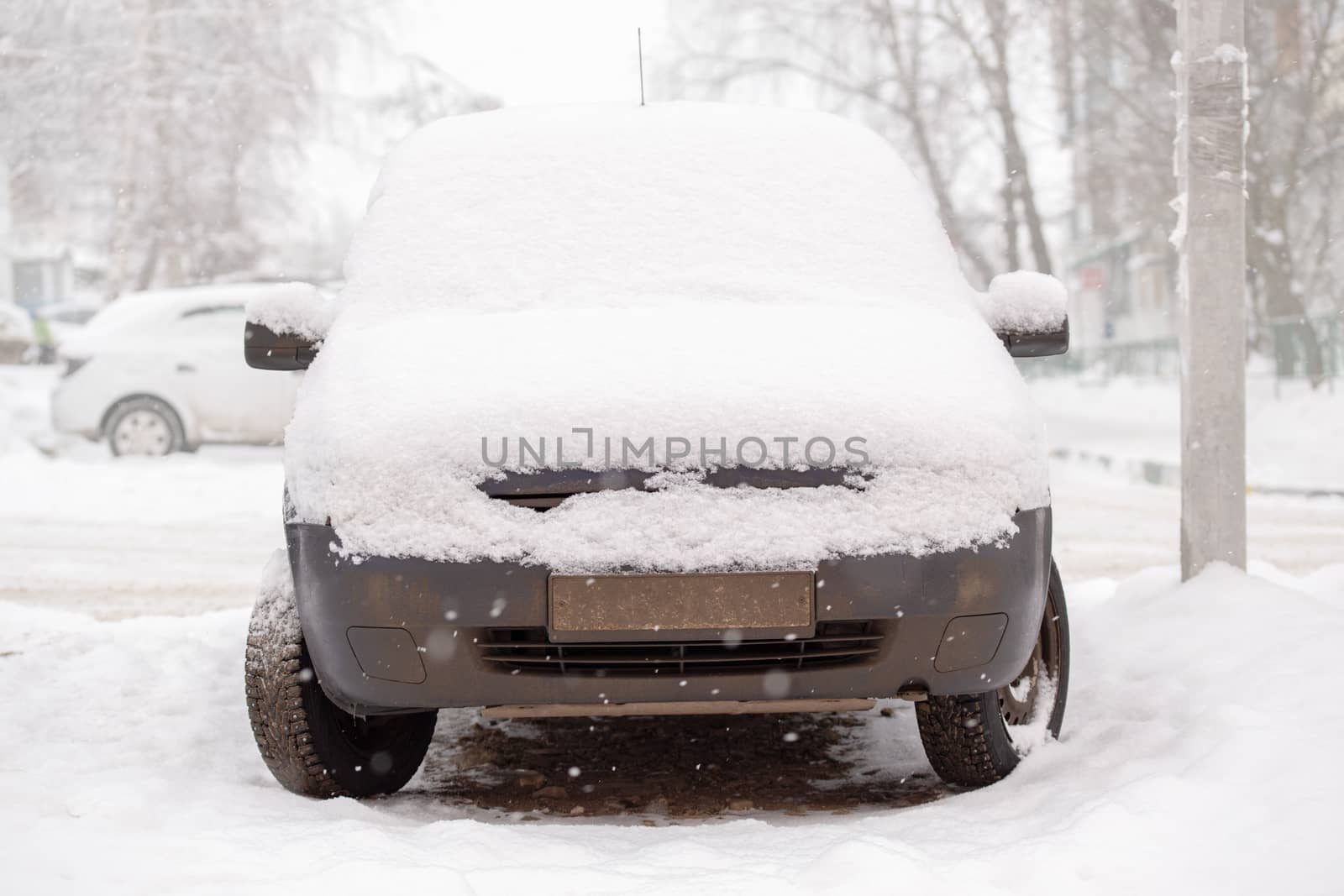 Old dirty car covered by thick snow layer with selective focus.