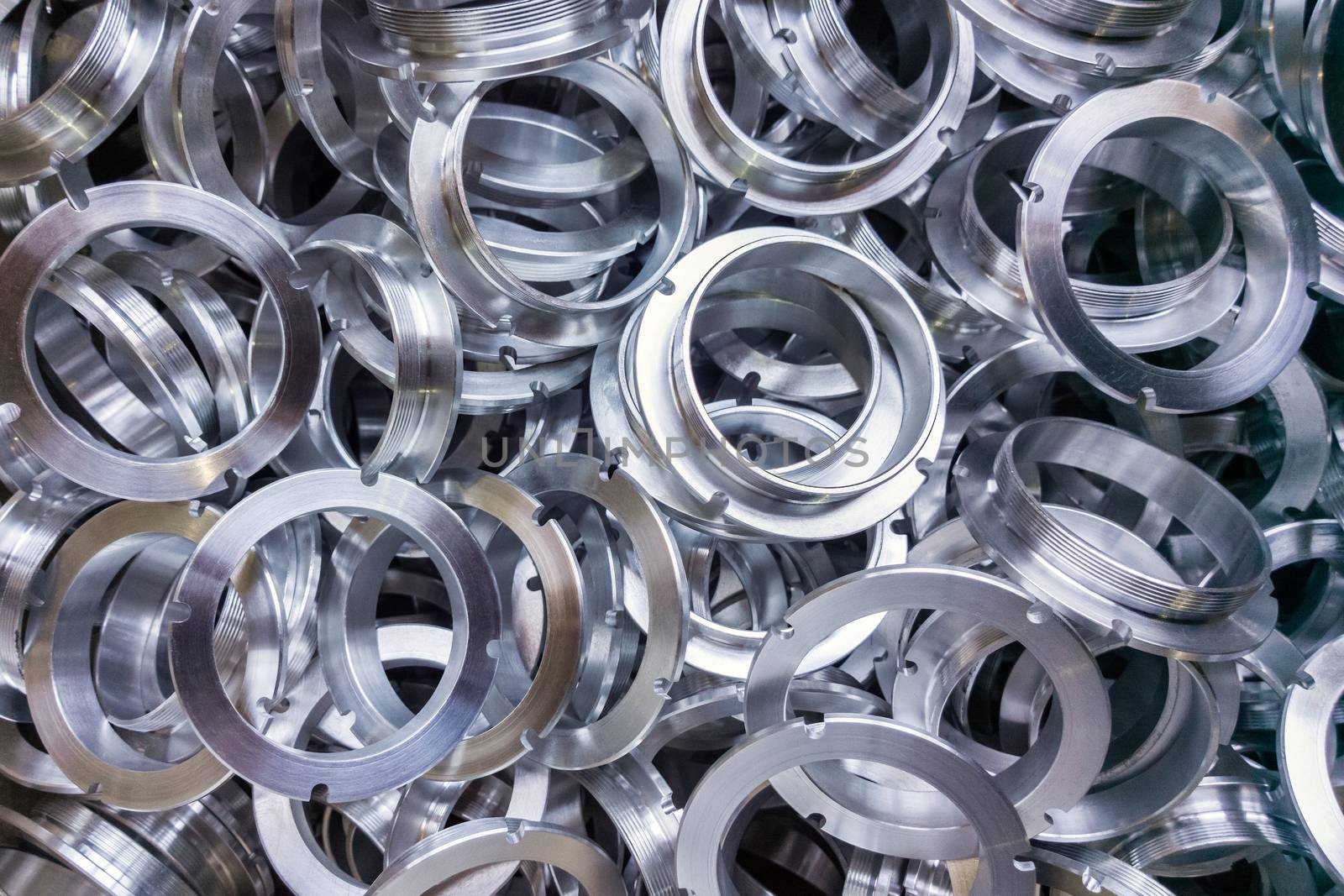 a batch of machined shiny aluminium parts with selective focus.