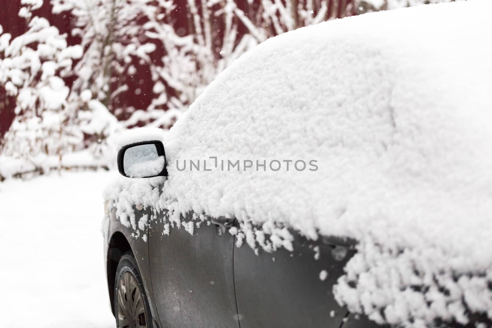Dirty car covered by thick snow layer with selective focus.