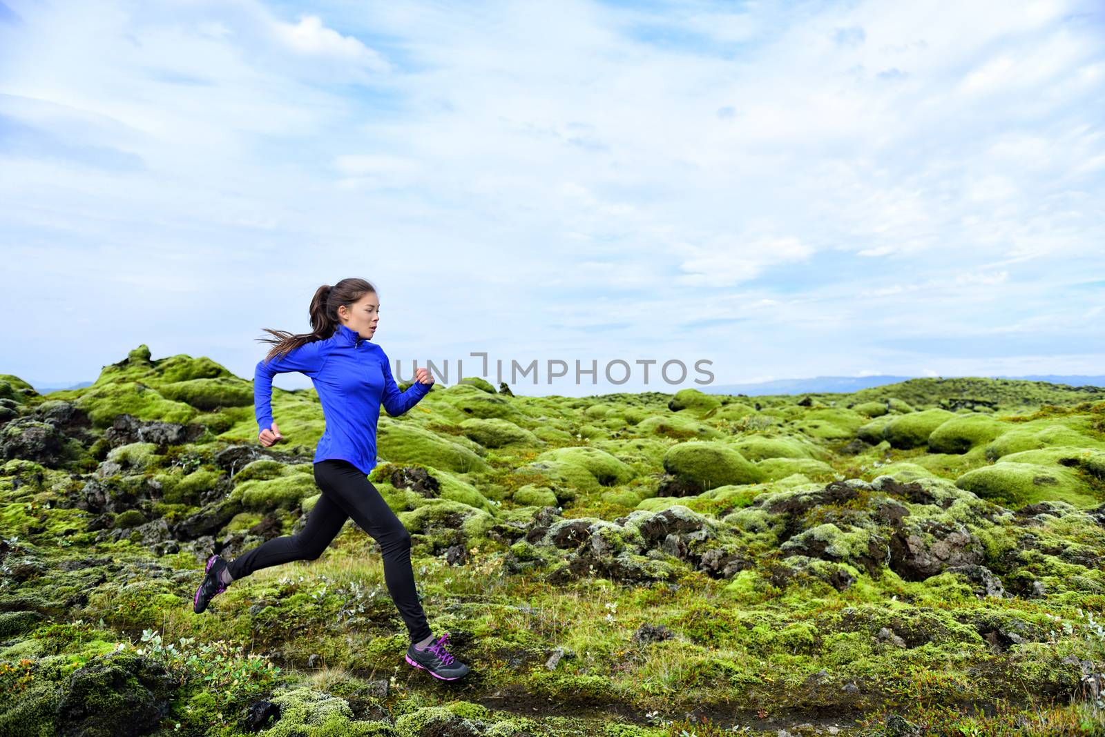 Woman running. Trail runner in cross country run. Female runner training jogging outdoors in mountain nature landscape on Iceland. Healthy lifestyle mixed race fitness model by Maridav