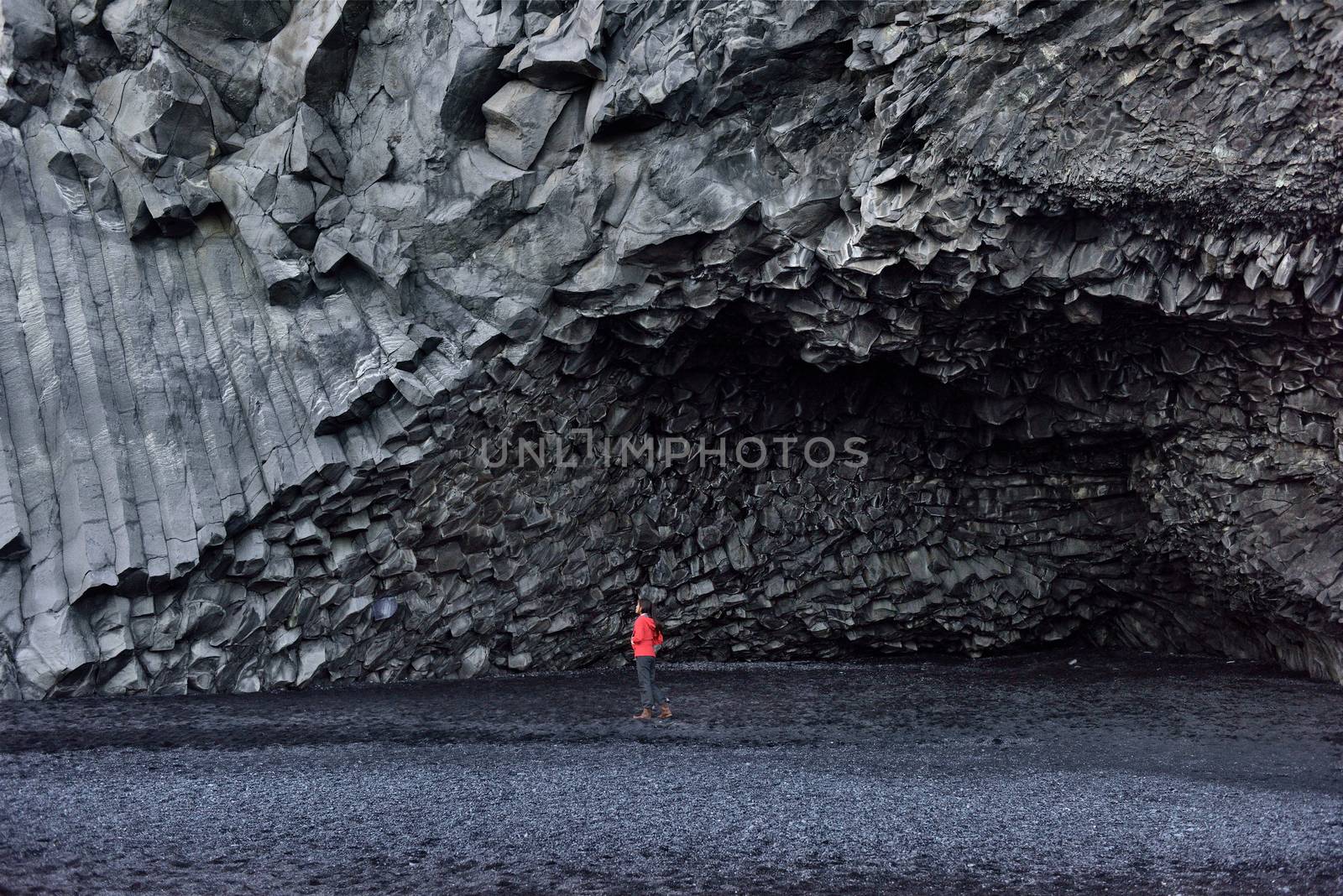 Iceland tourist woman walking on Reynisfjara black sand beach by basalt columns and cave, beach of Vik, South Iceland coast. Happy woman visiting tourist attraction destination by Maridav